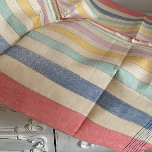 Könnte beinhalten: Ein gestreiftes Stoff-Geschirrtuch mit verschiedenen Farben wie Rot, Blau, Gelb, Grün und Pink. Der Stoff ist mit einer Leinenstruktur gewebt.