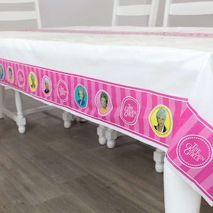 May include: A white plastic tablecloth with a pink and white striped border. The border features images of the four Golden Girls and the text "The Golden Girls".