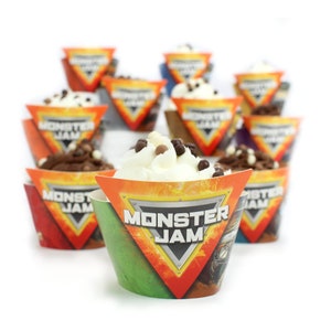 May include: A close-up of a cupcake with white frosting and chocolate sprinkles. The cupcake is in a colorful cupcake wrapper with the words "Monster Jam" printed on it. There are other cupcakes in the background.
