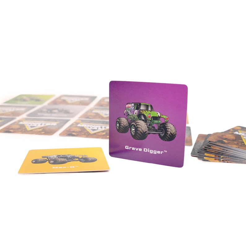 May include: A purple card with a green monster truck illustration and the text "Grave Digger". Other cards with monster truck images are visible. The cards are likely part of a game or collectible set.