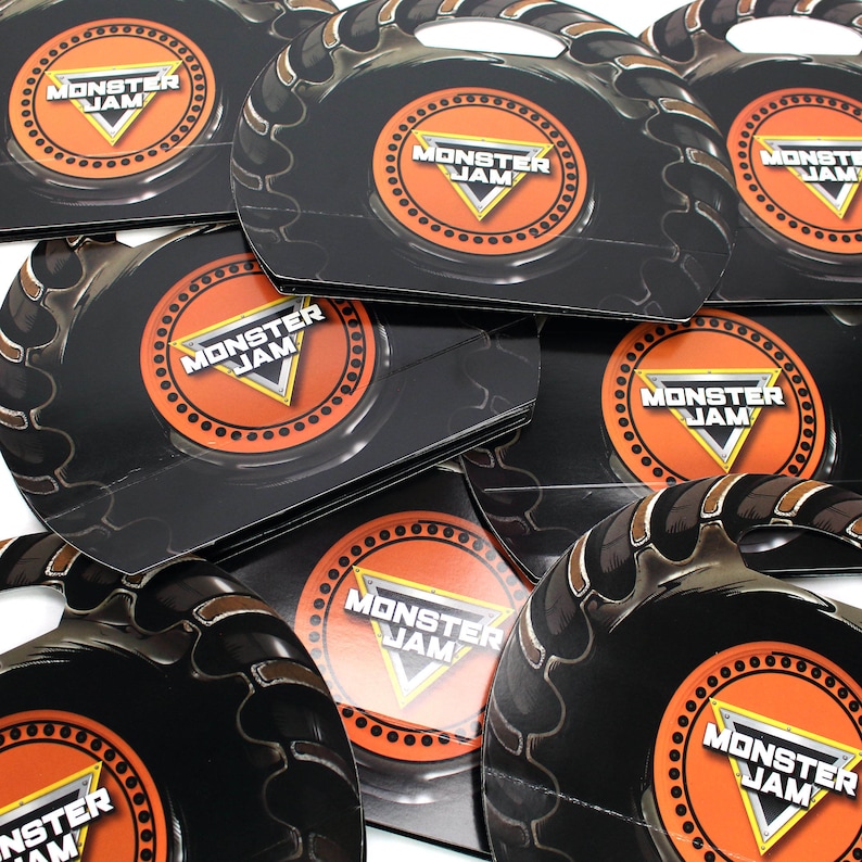 May include: A stack of black and orange Monster Jam party favor boxes with a tire tread design. Each box features a Monster Jam logo with the text "Monster Jam".