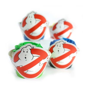 May include: Ghostbusters themed cupcake wrappers with a green, blue, and yellow frosting. The wrappers feature a white ghost with a red "no ghost" symbol.