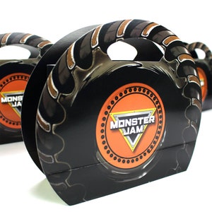 May include: Black and orange Monster Jam party favor box with a tire tread design and a Monster Jam logo. The box has a handle for easy carrying.