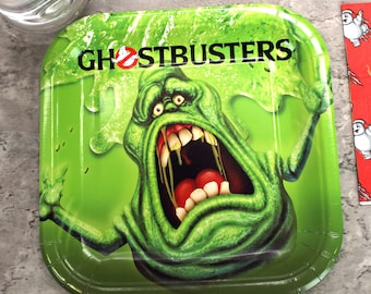 May include: Green paper party plate with a green ghost with a big mouth and red teeth. The ghost is surrounded by green slime. The text "Ghostbusters" is printed in black at the top of the plate.