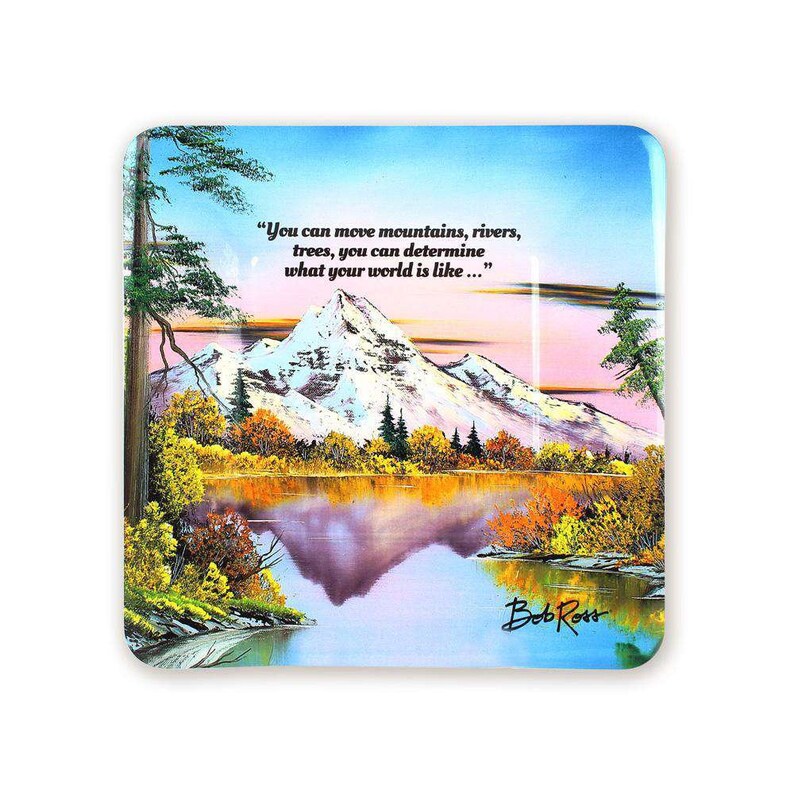 Pode incluir: Um descanso de copo quadrado de vidro com uma pintura de uma cordilheira refletida num lago. O c&eacute;u &eacute; azul claro com nuvens cor-de-rosa. A cita&ccedil;&atilde;o "You can move mountains, rivers, trees, you can determine what your world is like..." est&aacute; impressa na parte superior do descanso de copo. A assinatura do artista "Bob Ross" est&aacute; impressa na parte inferior do descanso de copo.