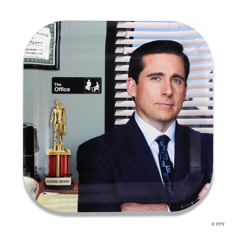 May include: A square paper plate featuring a photo of Michael Scott from the TV show "The Office". The plate has a blue and white striped background with a gold award trophy and a sign that says "The Office" in the background.