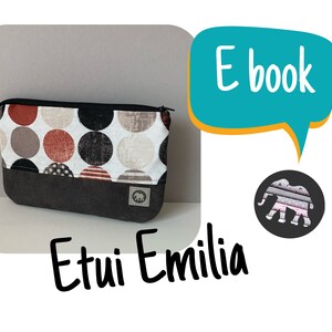 May include: A rectangular fabric pouch with a black zipper closure. The upper section features a pattern of large circles in red, black, and beige. The lower section is solid dark gray with a small square patch displaying an elephant icon. Text reads E book and Etui Emilia.