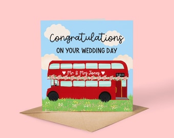 May include: A wedding card featuring a red double-decker bus decorated with flowers. The card reads "Congratulations on Your Wedding Day" above the bus, with the names "Mr & Mrs Jones" and a date on the bus.