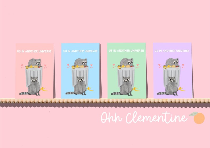A greeting card with an illustration of two raccoons and the text ''Us In Another Universe"