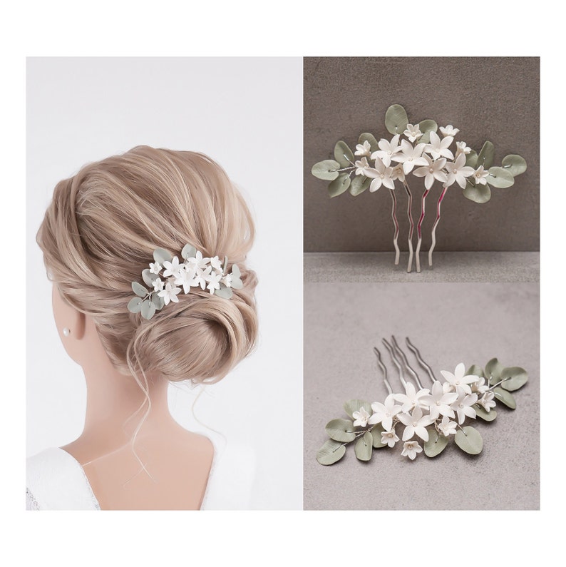 May include: A bridal hair comb featuring white flower accents and sage green leaves. The comb is made of metal and is designed to be worn in the hair. The image shows the comb in use and as a standalone accessory.
