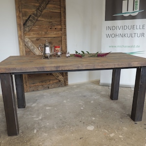 Dining table made from cut half-timbered beams with raw steel