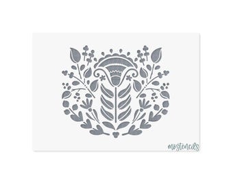 May include: A rectangular stencil featuring a gray symmetrical floral pattern with a central stylized flower, leaves, and berries. The design is centered on a white background with the text mostencils printed in the bottom right corner.