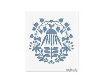May include: A square stencil featuring a blue botanical design with a central flower, leaves, and vines arranged in a symmetrical pattern. The text "mostencils" is printed in a small, cursive font in the bottom right corner of the sheet.