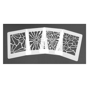 Può includere: Un set di quattro stencil rettangolari bianchi con distinti motivi floreali e astratti. Ogni stencil presenta un design ritagliato con forme organiche, inclusi raggi solari, forme simili a petali e linee fluide disposte in fila.