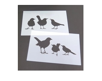 May include: Two rectangular white plastic stencils featuring black bird silhouettes. The top stencil displays three distinct birds standing in a row. The bottom stencil shows a different arrangement of three birds, including one larger bird and two smaller ones.