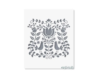 May include: A square stencil featuring a symmetrical gray folk art design on a white background. The pattern includes two birds facing each other, surrounded by stylized flowers, leaves, and berries. The text mostencils is printed in the bottom right.