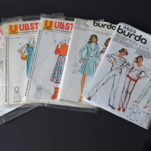 May include: Five different sewing patterns for clothing. The patterns are in plastic sleeves and feature illustrations of women wearing the garments. The patterns are labeled "Ullstein" and "Burda" with numbers.