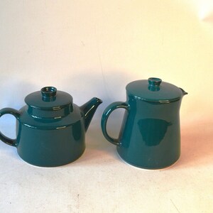 Pu&ograve; includere: Un set da t&egrave; in color turchese composto da una teiera e un creamer. La teiera ha un corpo rotondo e un beccuccio laterale. Il creamer ha un corpo alto e sottile.