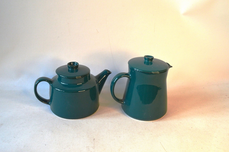 Pu&ograve; includere: Un set da t&egrave; in color turchese composto da una teiera e un creamer. La teiera ha un corpo rotondo e un beccuccio laterale. Il creamer ha un corpo alto e sottile.