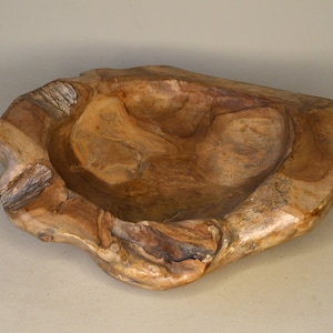 Può includere: Una grande ciotola di legno rustica con una finitura naturale marrone. La ciotola è scolpita da un unico pezzo di legno e ha una forma organica unica.
