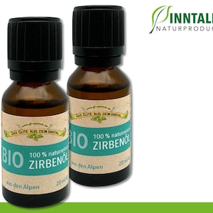 Puede incluir: Dos botellas de vidrio marrón con tapas negras, cada una con 20 ml de aceite de pino 100% natural. Las botellas tienen una etiqueta verde y blanca con el texto "BIO Zirbenöl aus den Alpen" y "Das Gute aus dem Inntal".