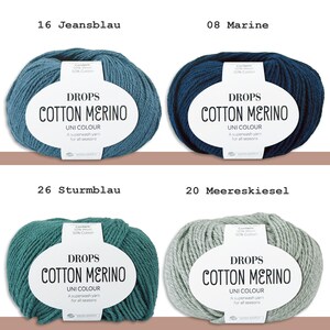 May include: Four skeins of Drops Cotton Merino yarn in various colors: denim blue, navy blue, teal, and light gray. Each skein has a white label with the brand name and yarn details. The text "UNI COLOUR" and "A superwash yarn for all seasons" are also visible.