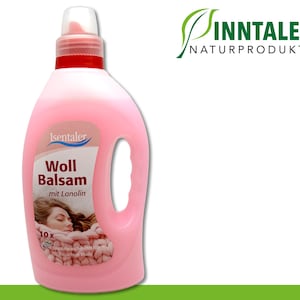 Puede incluir: Una botella de plástico rosa de Isentaler Woll Balsam con tapa blanca y detalles rojos. La etiqueta presenta texto y una imagen de una mujer envuelta en una manta de punto. El logotipo de Inntaler Naturprodukte es visible.
