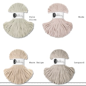K&ouml;nnte beinhalten: Vier Str&auml;nge Bobbiny-Kordel in einer Rasteranordnung. Die Farben sind als Pale Olive, Nude, Warm Beige und Leopard beschriftet. Jeder Strang ist mit einer wei&szlig;en Papierbanderole mit dem schwarzen Bobbiny-Logo versehen, die die Textur zeigt.