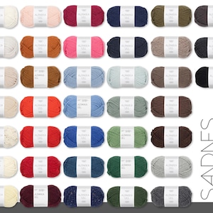 May include: A collection of colorful yarn skeins, each labeled "ALPAKKA ULL." The yarn is arranged in rows, showcasing a variety of hues including white, pink, red, blue, green, and brown. The brand name "SANDNES GARN" is displayed vertically on the right.