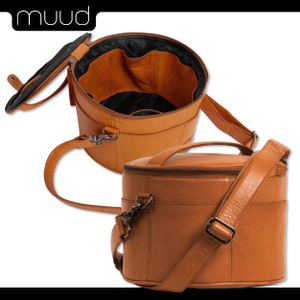 May include: A brown leather cylindrical travel bag with a zippered top and a long adjustable strap. The bag is open to reveal a brown fabric interior with multiple compartments.