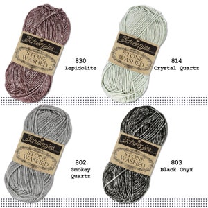 K&ouml;nnte beinhalten: Vier Kn&auml;uel Scheepjes Stone Washed Garn in verschiedenen Farben: Lepidolith, Kristallquarz, Rauchquarz und Schwarz Onyx. Jedes Kn&auml;uel hat ein Etikett mit dem Markennamen und der Garnart.