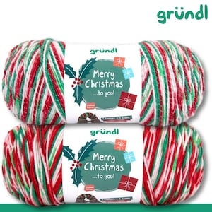 Könnte beinhalten: Zwei Garnknäuel mit einem mehrfarbigen Muster in Rot, Grün und Weiß. Jedes Knäuel hat eine weiße Papierbanderole mit dem Text Merry Christmas ...to you!, einer Stechpalmen-Illustration und kleinen Geschenken. Der Markenname gründl ist auf der Banderole gedruckt.
