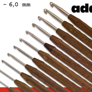 May include: A set of 10 wooden crochet hooks with metal tips, ranging in size from 2.0 to 6.0 mm. The hooks are arranged in a fan shape, with the largest hook at the top and the smallest hook at the bottom. The hooks are made of a dark brown wood with a natural finish. The metal tips are shiny and silver in color. The hooks are labeled with their size in millimeters. The brand name "addi" is printed on the top right corner of the image.