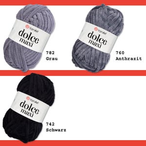 May include: Three balls of yarn in different colors: gray, dark gray, and black. Each ball has a label that says "YarnArt dolce maxi" and a number. The numbers are 782, 760, and 742. The colors are labeled as Grau, Anthrazit, and Schwarz.