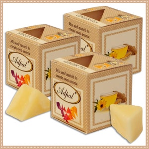 Puede incluir: Tres cajas de té de jengibre Adpal, cada una con una pequeña ventana que muestra una ilustración de taza de té y raíz de jengibre. Las cajas son de color beige con lunares blancos y el texto "Mix and match to create own aroma". Dos ceras aromáticas triangulares amarillas en primer plano.