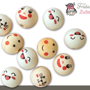 May include: Ten wooden beads with different painted faces. The faces include a cat, a smiling face with red cheeks, a surprised face, a winking face, a sleeping face, a happy face, a sad face, a laughing face, a frowning face, and a face with a tongue sticking out.