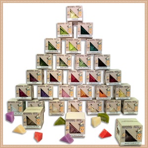 Pode incluir: Uma pirâmide de produtos de fragrância Aroma Mits, com aromas como Baunilha, Canela e Chá de Gengibre. Cada caixa contém 8 peças. Peças de fragrância individuais, em cores como roxo, amarelo e vermelho, estão espalhadas na base.
