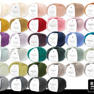 Puede incluir: Una colección de ovillos de lana gruesa Rico Design mega wool en varios colores, incluyendo crema, rosa, rojo y verde. Cada ovillo tiene una etiqueta blanca. La lana está dispuesta en filas, mostrando la gama de tonos disponibles para proyectos de punto y ganchillo.