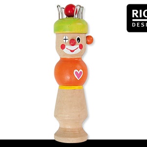 May include: A wooden clown toy with a red nose, green hat, and orange body. The clown has a painted face with a smile, a heart, and a plus sign. The toy has a metal ring on top for hanging.