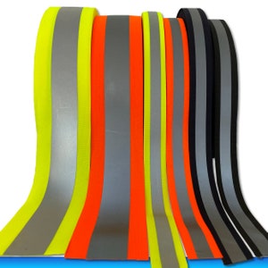 Puede incluir: Surtido de cintas reflectantes y no reflectantes en varios colores, incluyendo amarillo, naranja, gris y negro. Las cintas están dispuestas en una fila, con las tiras reflectantes alternando con las tiras no reflectantes.