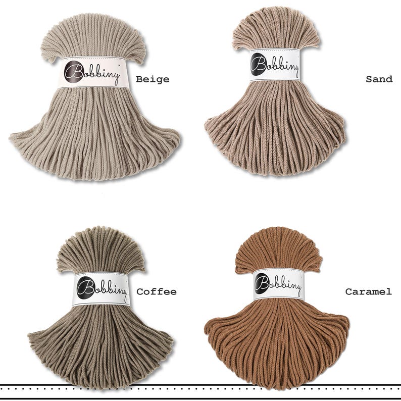 K&ouml;nnte beinhalten: Vier Str&auml;nge aus Bobbiny-Baumwollkordel in einem Raster angeordnet, jeder mit einer wei&szlig;en Papierbanderole mit dem Text Bobbiny versehen. Die Farben sind als Beige, Sand, Coffee und Caramel gekennzeichnet und zeigen verschiedene Braun- und Beiget&ouml;ne.
