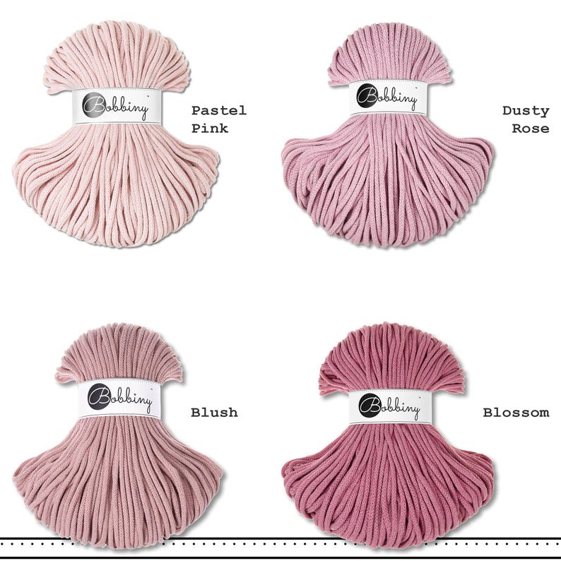 May include: Four skeins of Bobbiny cotton cord arranged in a grid. Each skein features a white paper band with the brand name Bobbiny. The colors are labeled as Pastel Pink, Dusty Rose, Blush, and Blossom, showing varying shades of pink.