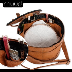 May include: A brown leather round sewing kit with a zipper closure. The kit is open and shows a white embroidery hoop, a measuring tape, and various sewing tools.