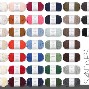 May include: A collection of colorful yarn skeins, each labeled "ALPAKKA ULL." The yarn is arranged in rows, showcasing a variety of hues including white, pink, red, blue, green, and brown. The brand name "SANDNES GARN" is displayed vertically on the right.