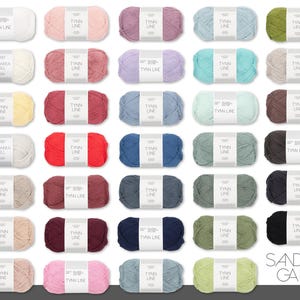 Könnte beinhalten: Eine Sammlung farbenfroher Garnknäuel, jeweils mit der Aufschrift "TYNN LINE" und "SANDNES GARN". Das Garn ist in einer Vielzahl von Farben erhältlich, darunter Weiß, Rosa, Lila, Blau, Grün und Braun. Das Bild ist gut beleuchtet.