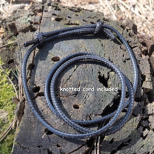 May include: A black braided cord with a knot at one end. The cord is coiled and laid on a wooden surface. "knotted cord included" is written on the surface.