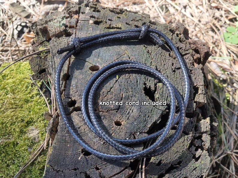 May include: A black braided cord with a knot at one end. The cord is coiled and laid on a wooden surface. "knotted cord included" is written on the surface.