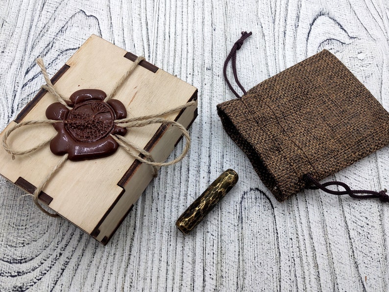 May include: A wooden box with a brown wax seal and a brown burlap pouch with a gold metal stamp inside.