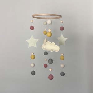 May include: A wooden hoop mobile with felt stars, clouds, and balls in shades of grey, white, yellow, and pink.