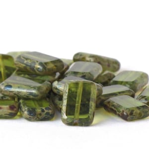 Op de afbeelding: Een stapel groene glazen kralen met een gevlekt, gemarmerd patroon. De kralen zijn rechthoekig van vorm en hebben een licht iriserende afwerking.